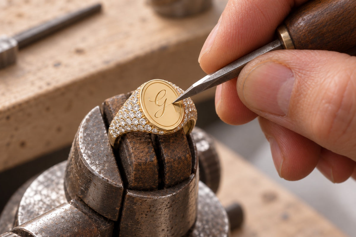Goldschmied graviert die Initiale G in einen Pavé-Siegelring aus 18k Gold
